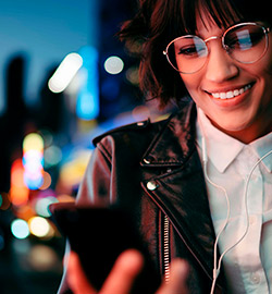 Mulher olhando o celular na rua de noite
