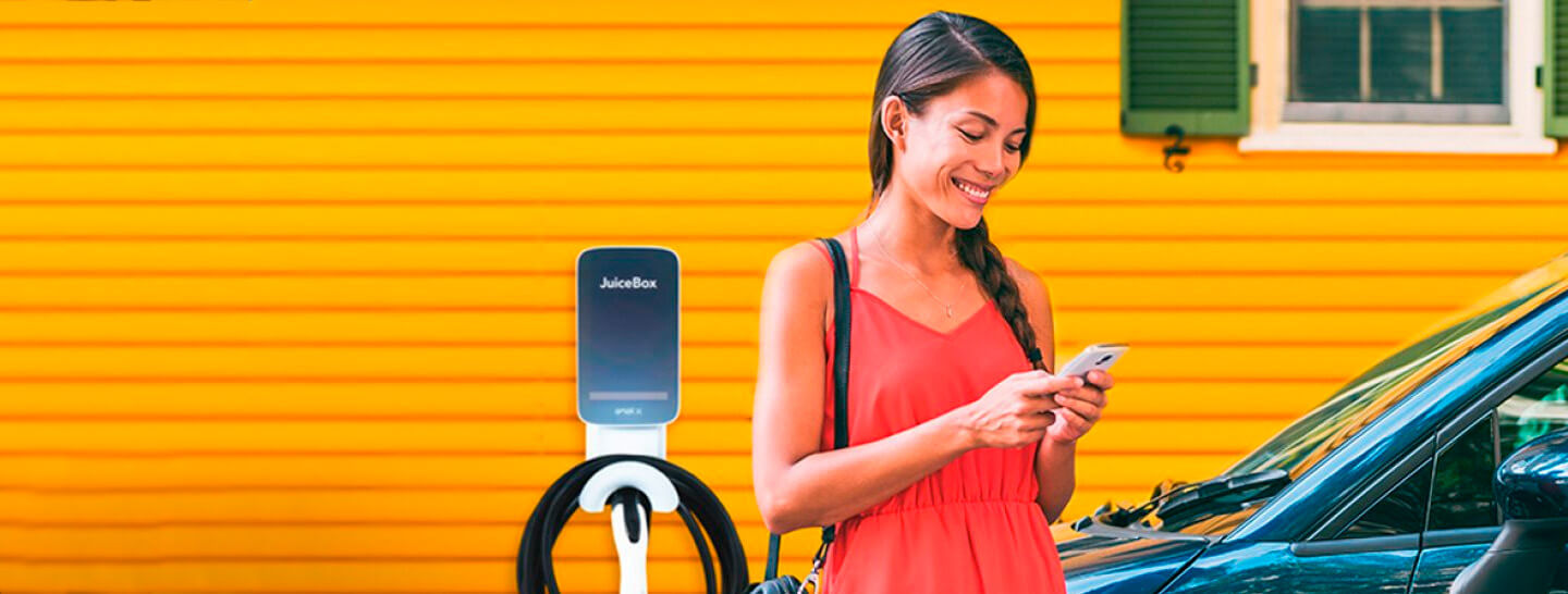 Mulher mexendo no celular enquanto seu carro carrega