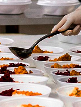 Várias marmitas com comida dentro e alguém servindo