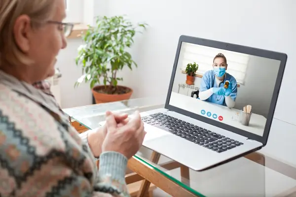 Señora mayor en consulta médica por videollamada, gracias a su asistencia médica.