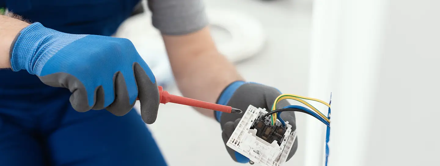 Hombre solucionando una falla en las instalaciones eléctricas residenciales, gracias a Enel X.