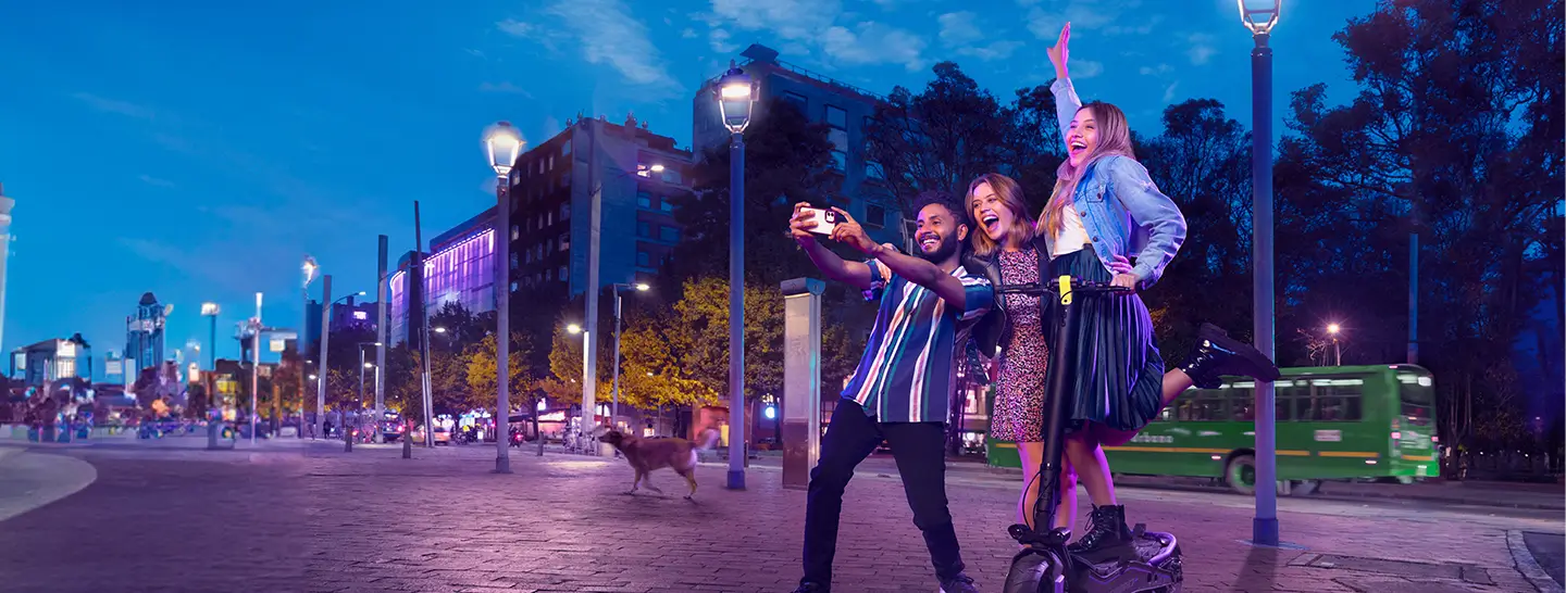 Tres jóvenes tomándose una foto en una ciudad inteligente, gracias a las soluciones energéticas que ofrece Enel X Colombia.