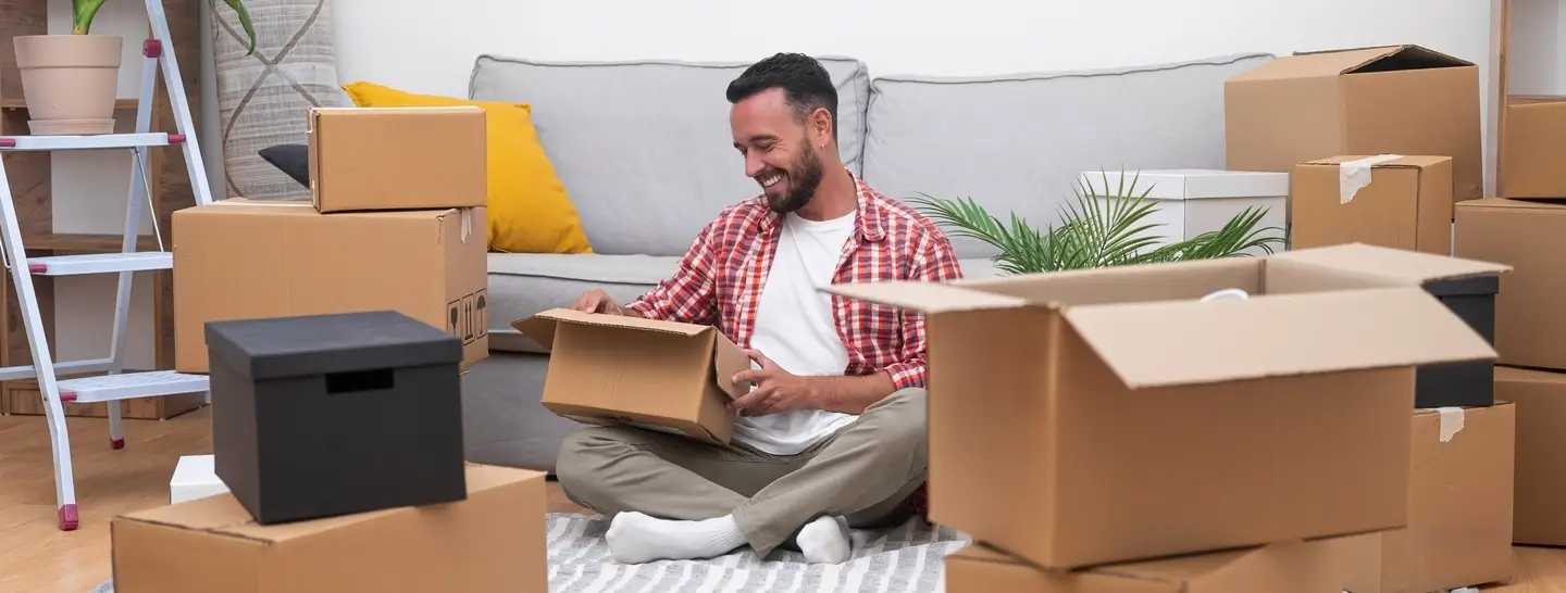 Un hombre feliz desempacando sus pertenencias después de independizarse.