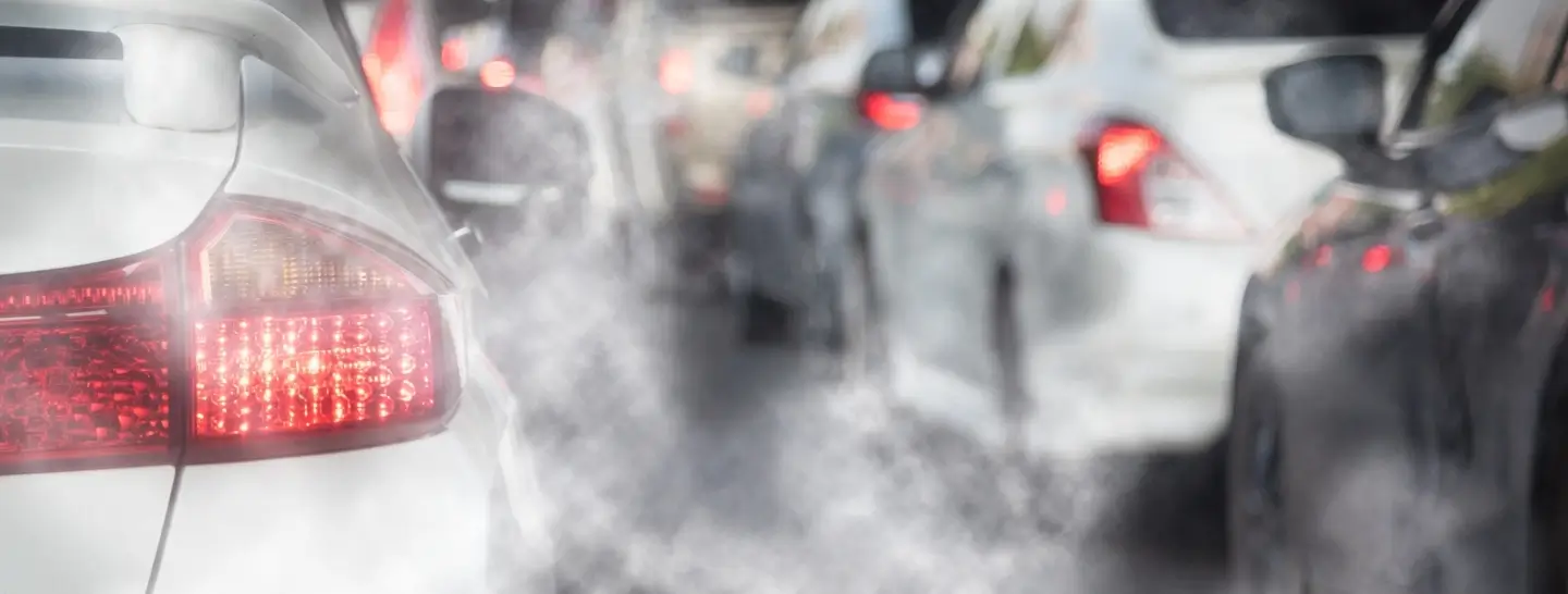Automóviles emitiendo partículas contaminantes al aire debido al uso de combustibles fósiles.