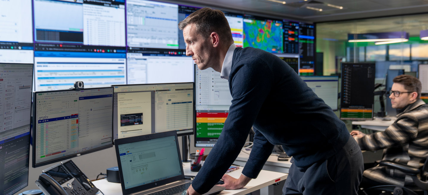 Energy market operators monitoring data across multiple screens in a modern control room