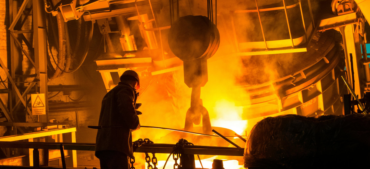Worker operating a furnace in a high-temperature metal processing facility