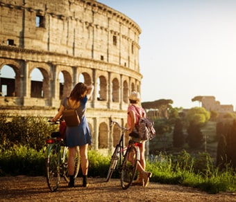 Due ragazze in bicicletta con il Colosseo sullo sfondo