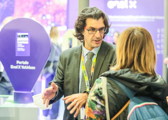 Tony Toro dialoga con un'ospite presso lo stand di Enel X ad ANCI