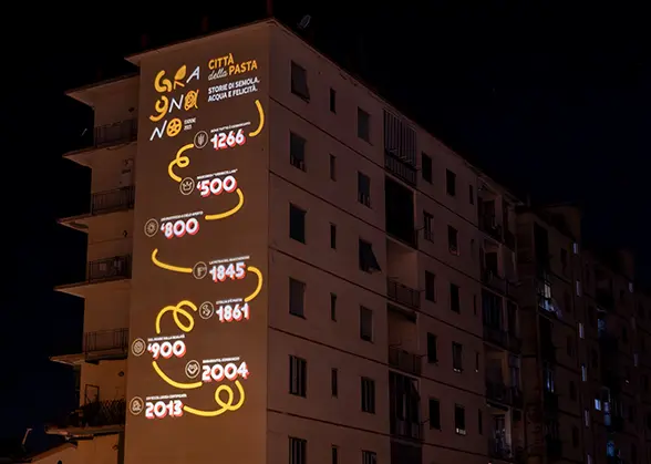 Proiezione luminosa artistica sulla facciata di un edificio a Gragnano