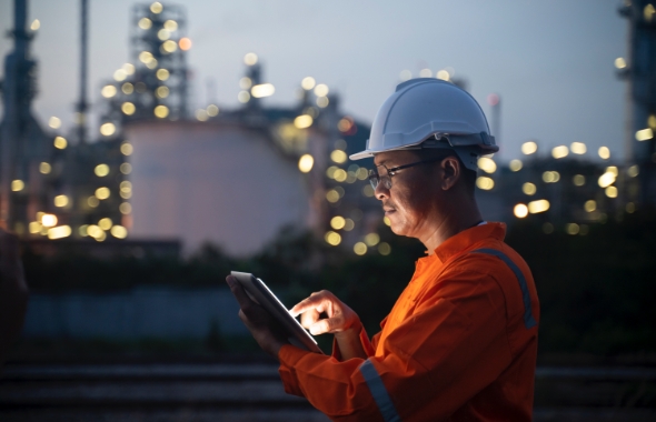 engineer using laptop outside industrial complex
