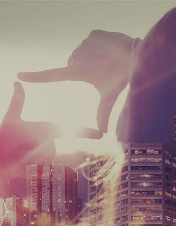 Woman's hands framing sun, double exposure with buildings in the backgroundOur Mission
