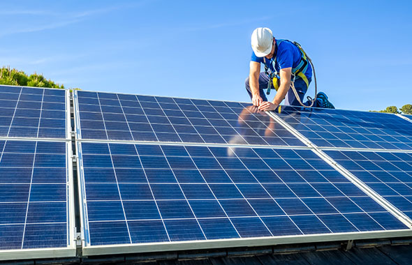worker installing solar panels on rooftop