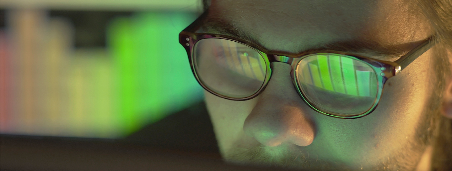 Person reviewing data on a computer screen with reflection in glasses