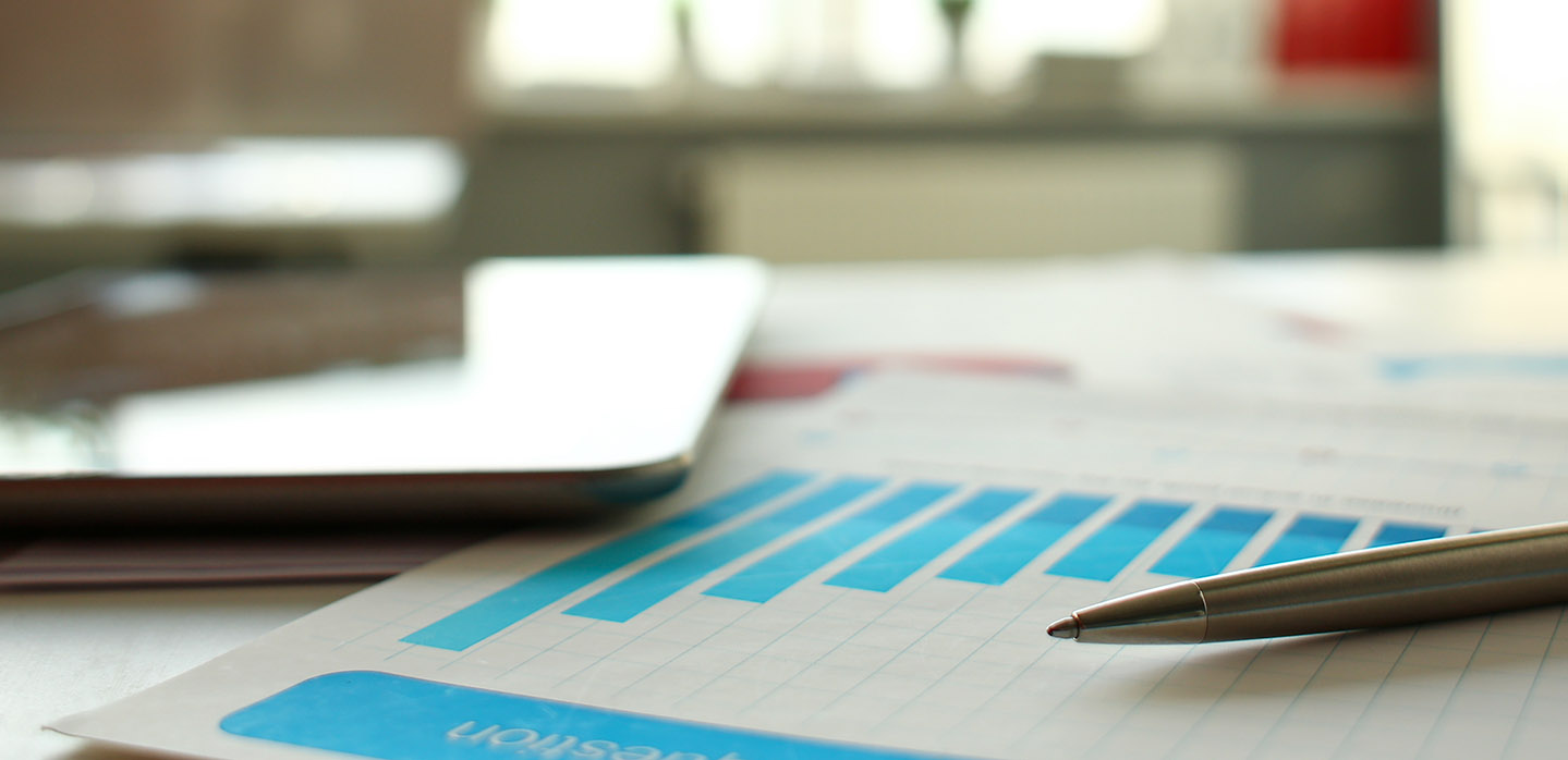 Printed charts and graphs on a desk with a tablet and pen