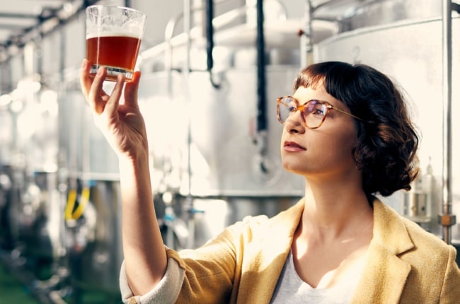 technician reviewing quality of beverage in a glass